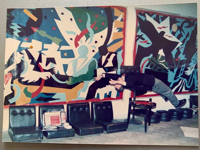(E-E) Evgenij Kozlov in his Leningrad studio “Russkoe Polee” / The Russian Field with two paintings from his "New Classicals" cycle 1989/1990: Love for the Cosmos and Love for the Wonderful (first version) more>> Colour print, 9 x 12.5 cm, with text on the reverse from Letter R, 18 March 1990 Photo: unknown. E-E archival number: E-E-pho-ZA04-op  Davis Center for Russian and Eurasian Studies Special Collection, Harvard University Harvard Accession Number: KMFP_0089